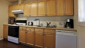 Una cocina con armarios de madera, estufa, lavavajillas y cafetera.
