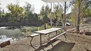 Una mesa de picnic bajo un toldo a rayas junto a un río.