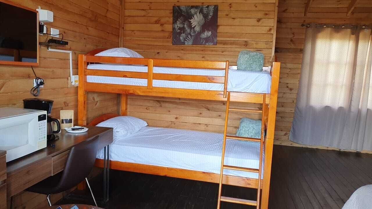 Ein Schlafraum mit Etagenbetten, einem Schreibtisch, einem Sessel, einer Mikrowelle und einem Bild an der Wand.