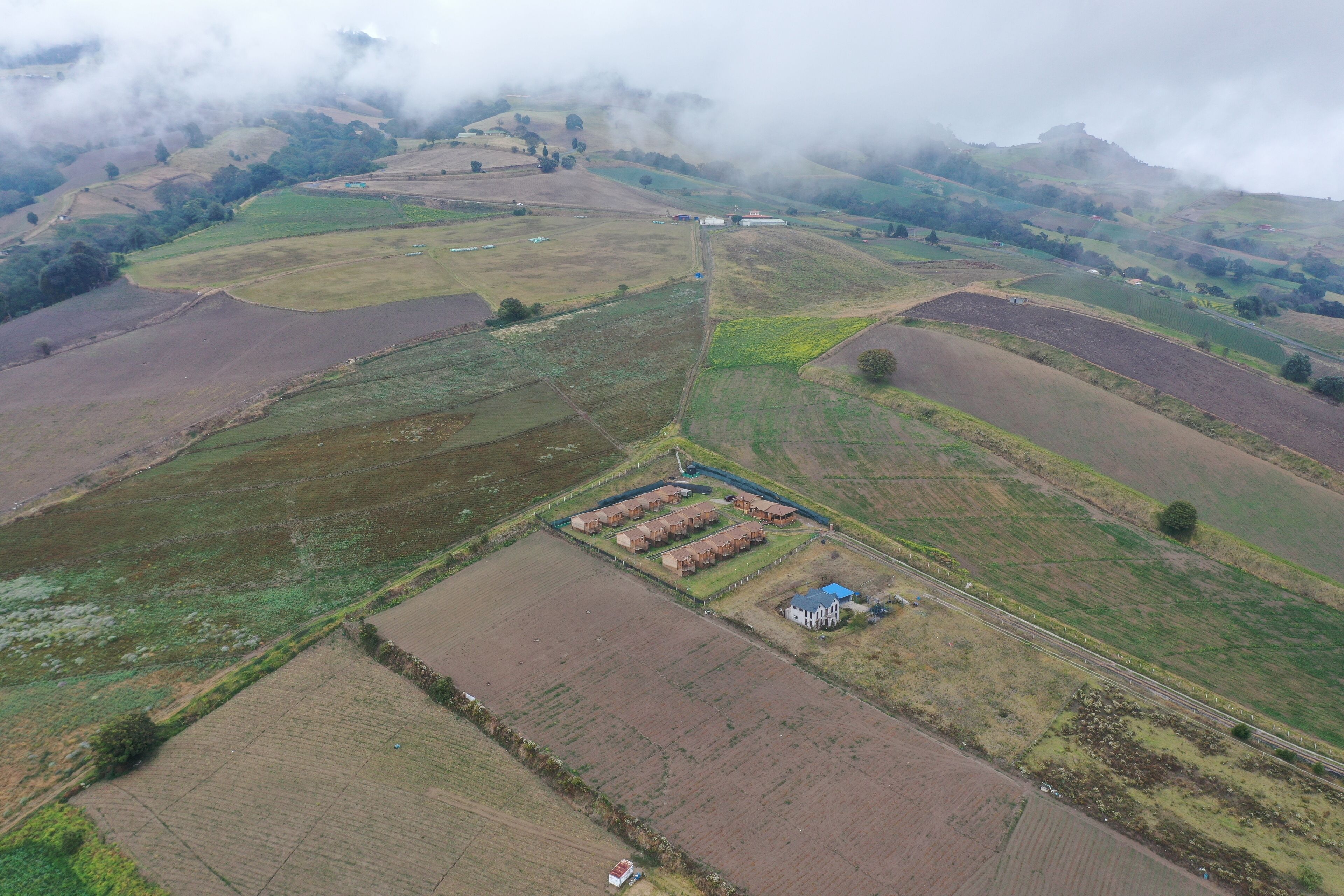 Vista aérea de un paisaje rural con campos, una casa de campo y una carretera.