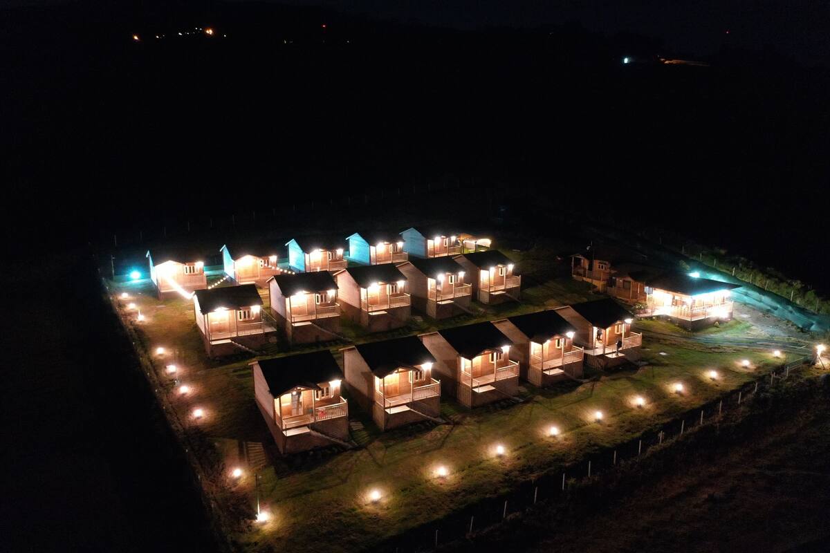 A row of uniformly lit cabins with a fenced perimeter, suggesting a resort or campground setting.