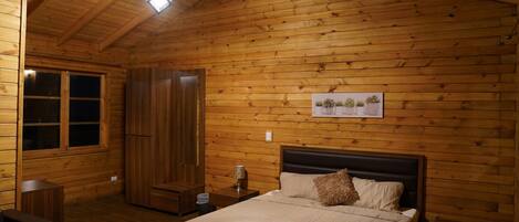 Habitación con paneles de madera, una cama, una mesita de noche, una ventana y una puerta.