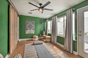 Relax in this serene space with a ceiling fan overhead, a window with curtains, and a comfortable rug underfoot.