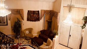 A living room with a staircase, a chandelier, a large plant, and a door. - Tranquil 4BR/3BA private house w/ inviting yard perfect for any type of stay (Fontana)