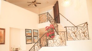 A staircase with ornate metal railings, a chandelier, and framed pictures on the walls. - Tranquil 4BR/3BA private house w/ inviting yard perfect for any type of stay (Fontana)