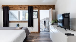 Ein Schlafzimmer mit Bett, Fernseher, Fenster und Balkon.