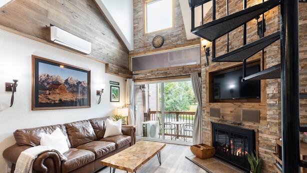 Ein großzügiges Wohnzimmer mit einer Ledersofa, einem Holztisch, einem Kamin und einem großen Fernseher.
