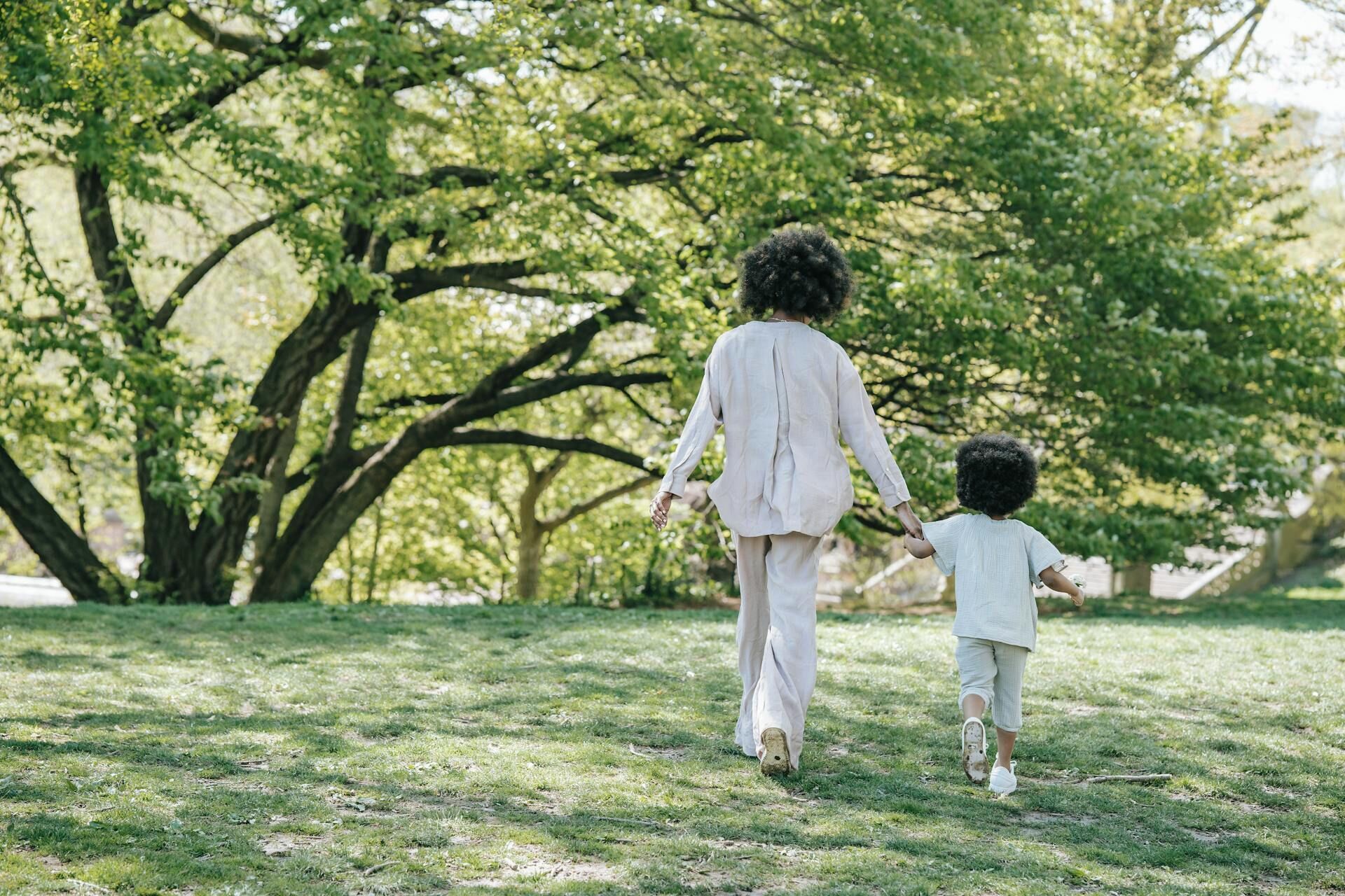 A person walking with a child in a park.