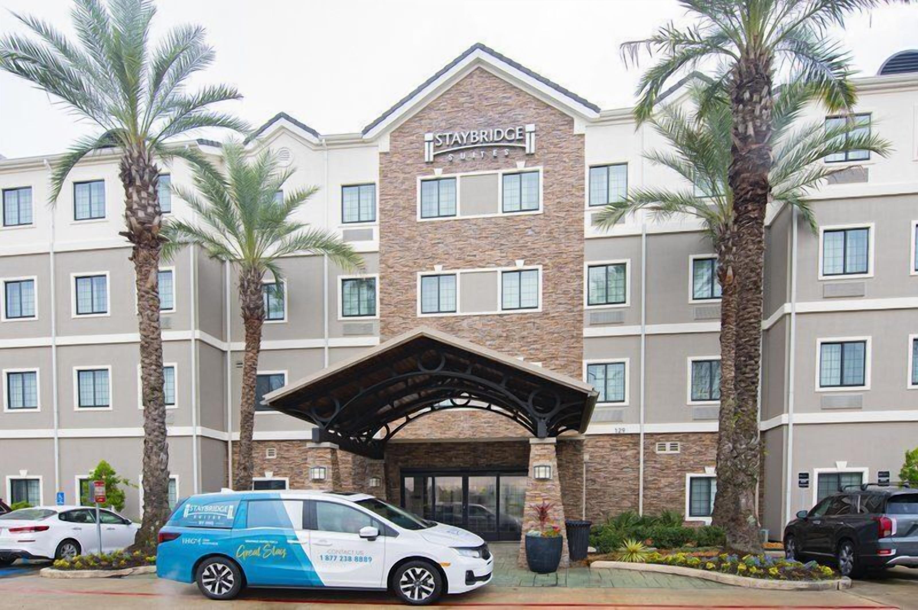 A Staybridge hotel with a stone facade, multiple windows, and a covered entrance.