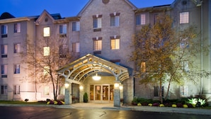 A multi-story hotel with a stone facade, a covered entrance, and a landscaped front yard. - Fully-Equipped Suite | Complimentary Breakfast (Oakbrook Terrace)