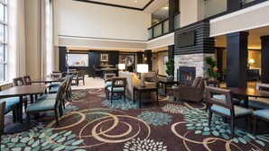 A spacious lobby with a high ceiling, multiple seating areas, and a fireplace. - Fully-Equipped Suite | Complimentary Breakfast (Oakbrook Terrace)