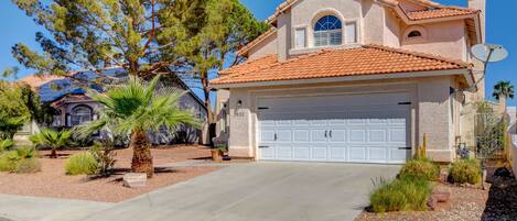 A residential house with a garage, a satellite dish, and a well-maintained front yard with various plants.
