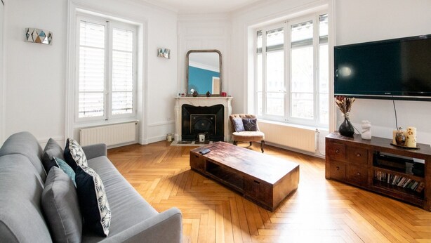 A spacious living room with a fireplace, a large TV, and a wooden coffee table. - 128 Thiers (Villeurbanne)