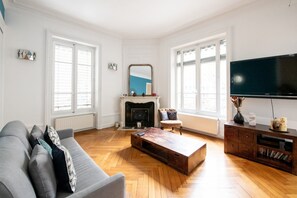 Un salon spacieux avec une cheminée, un grand téléviseur et une table basse en bois.