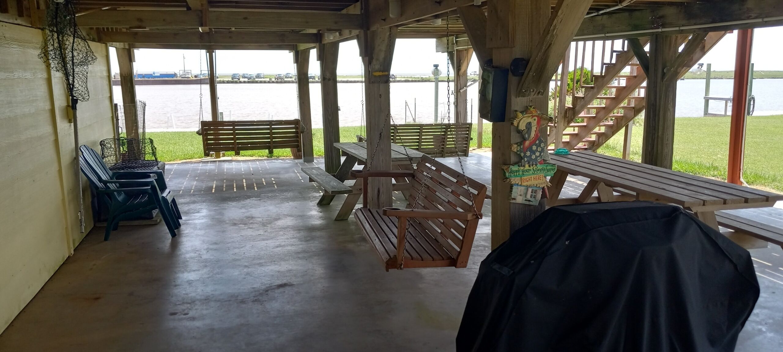 A covered outdoor area with benches and picnic tables, overlooking a body of water.