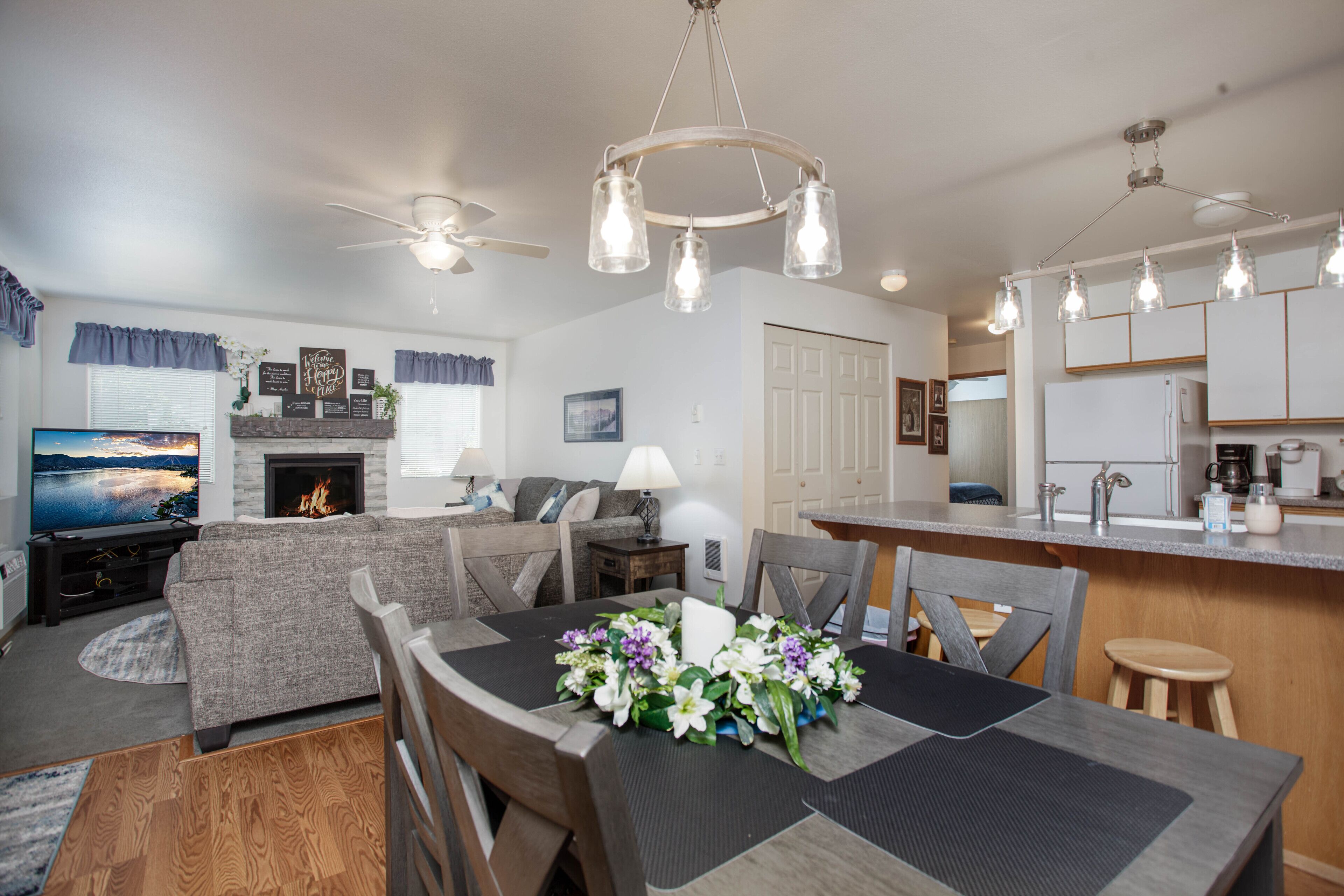 Una sala de estar moderna con chimenea, una mesa de comedor con sillas, una zona de cocina y un televisor.