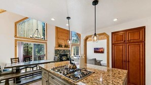 A kitchen with a granite countertop, wooden cabinets, a gas stove, and pendant lighting. - 11 Beds, Walk to Pool and Hot Tub, Game Room (Truckee)