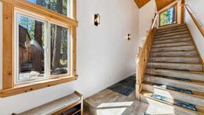 A staircase with wooden steps and a handrail, leading to a landing with a bench and a window. - 11 Beds, Walk to Pool and Hot Tub, Game Room (Truckee)