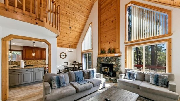 A spacious living area with a fireplace, wooden ceiling, and large windows. - 11 Beds, Walk to Pool and Hot Tub, Game Room (Truckee)