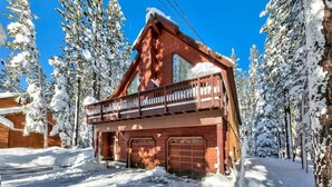 A wooden cabin with a balcony, surrounded by snow-covered trees. - 11 Beds, Walk to Pool and Hot Tub, Game Room (Truckee)