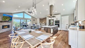 A modern kitchen with a dining area, large windows, and a fireplace. - Mountain Base Camp: Hot Tub, A/C, Dog Friendly (South Lake Tahoe)