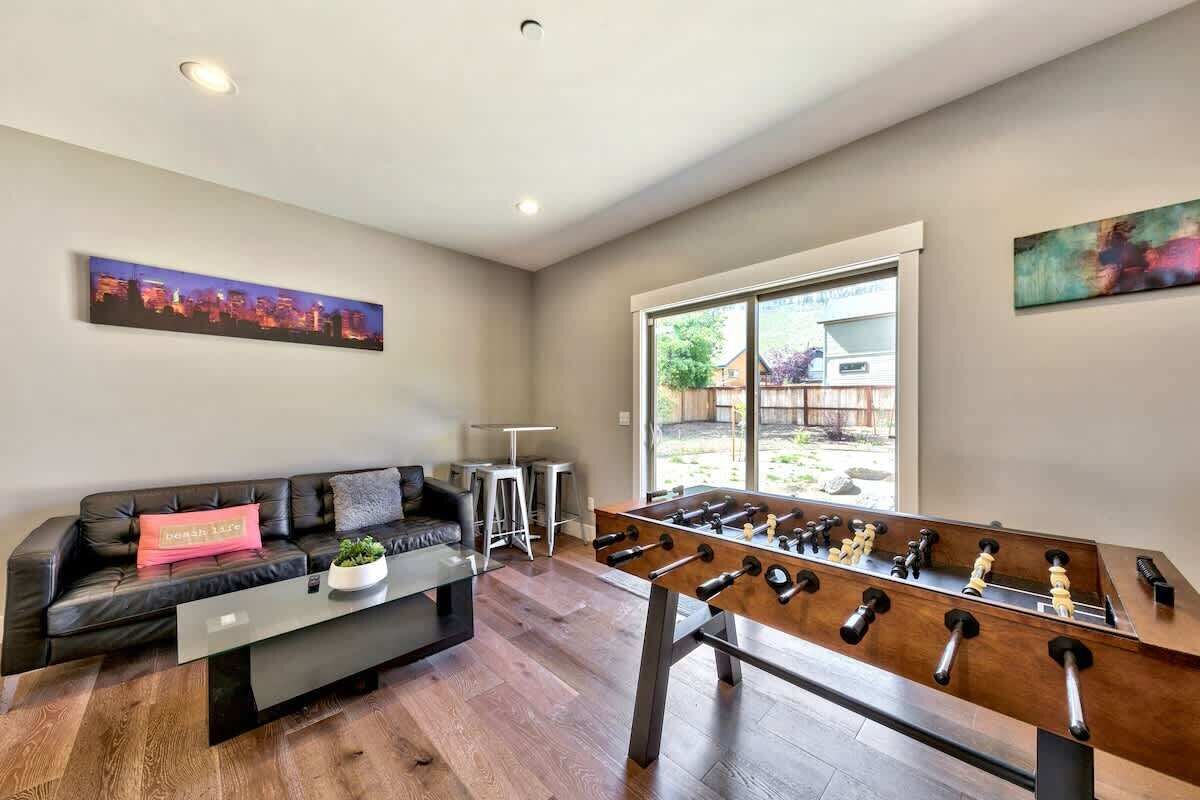 A living room with a sofa, coffee table, and foosball table.