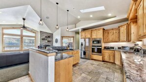 Una cocina amplia con armarios de madera, una isla grande y piso de baldosas de piedra.