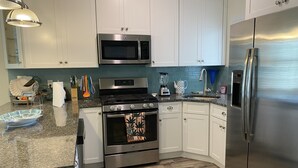 A modern kitchen with white cabinets, stainless steel appliances, granite countertops, and a wooden floor. - Mermaid Place is only 5 min walk to the beach. (Seaside Heights)