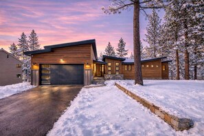 A modern two-story house with a garage, surrounded by snow-covered trees. - PeakView Tahoe: Hot Tub, Bar, Game Room, Trails (South Lake Tahoe)