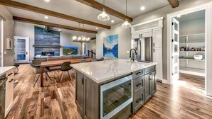 A modern kitchen with a large island, wooden beams, pendant lighting, and a view to the living area. - PeakViewTahoe: Hot Tub, AC, Game Room, ProjectorTV (South Lake Tahoe)