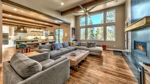 A modern living room with a sectional sofa, a fireplace, and large windows. - PeakViewTahoe: Hot Tub, AC, Game Room, ProjectorTV (South Lake Tahoe)