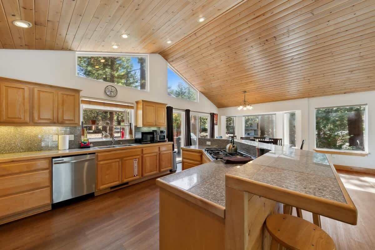 Una cocina moderna con armarios de madera, electrodomésticos de acero inoxidable y ventanas amplias.