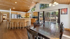 A spacious kitchen with wooden cabinets, a large island with stools, and a dining area with a wooden table and chairs.