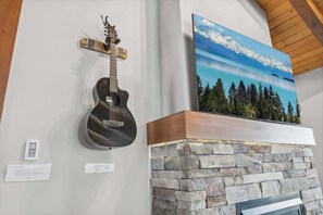 A guitar, a painting of a mountain landscape, and a stone fireplace. - Tahoe Treehouse: Hot Tub, Near Northstar, Views (Tahoe Vista)