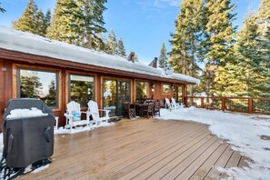 A wooden deck with outdoor seating, a covered grill, and a view of tall evergreen trees. - Tahoe Treehouse: Hot Tub, Near Northstar, Views (Tahoe Vista)