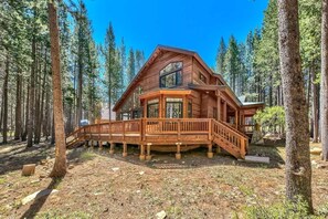 A cabin with a deck, surrounded by tall pine trees. - Large Cabin, Golf Views, Bunk Room, Game Loft (Truckee)