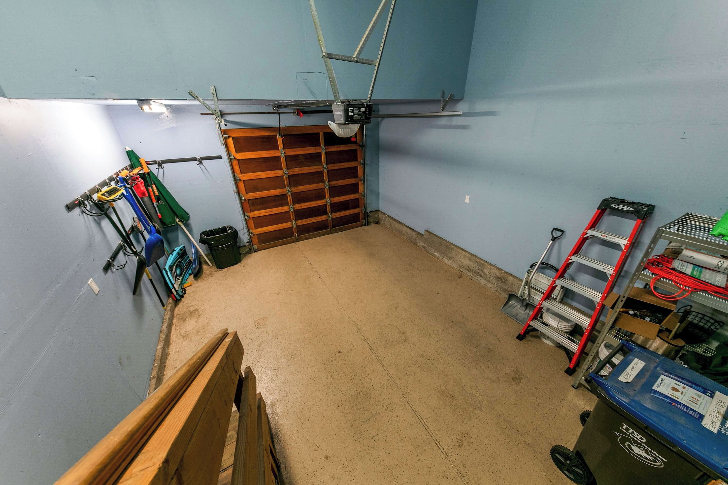 Een garage met een houten deur, gereedschap en een werkbank.