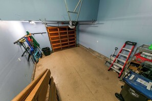 Ett garage med en trädörr, verktyg och en arbetsbänk.