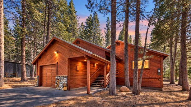 A wooden cabin with a garage, a staircase, and a stone wall.