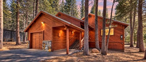 A wooden cabin with a garage, a staircase, and a stone wall.