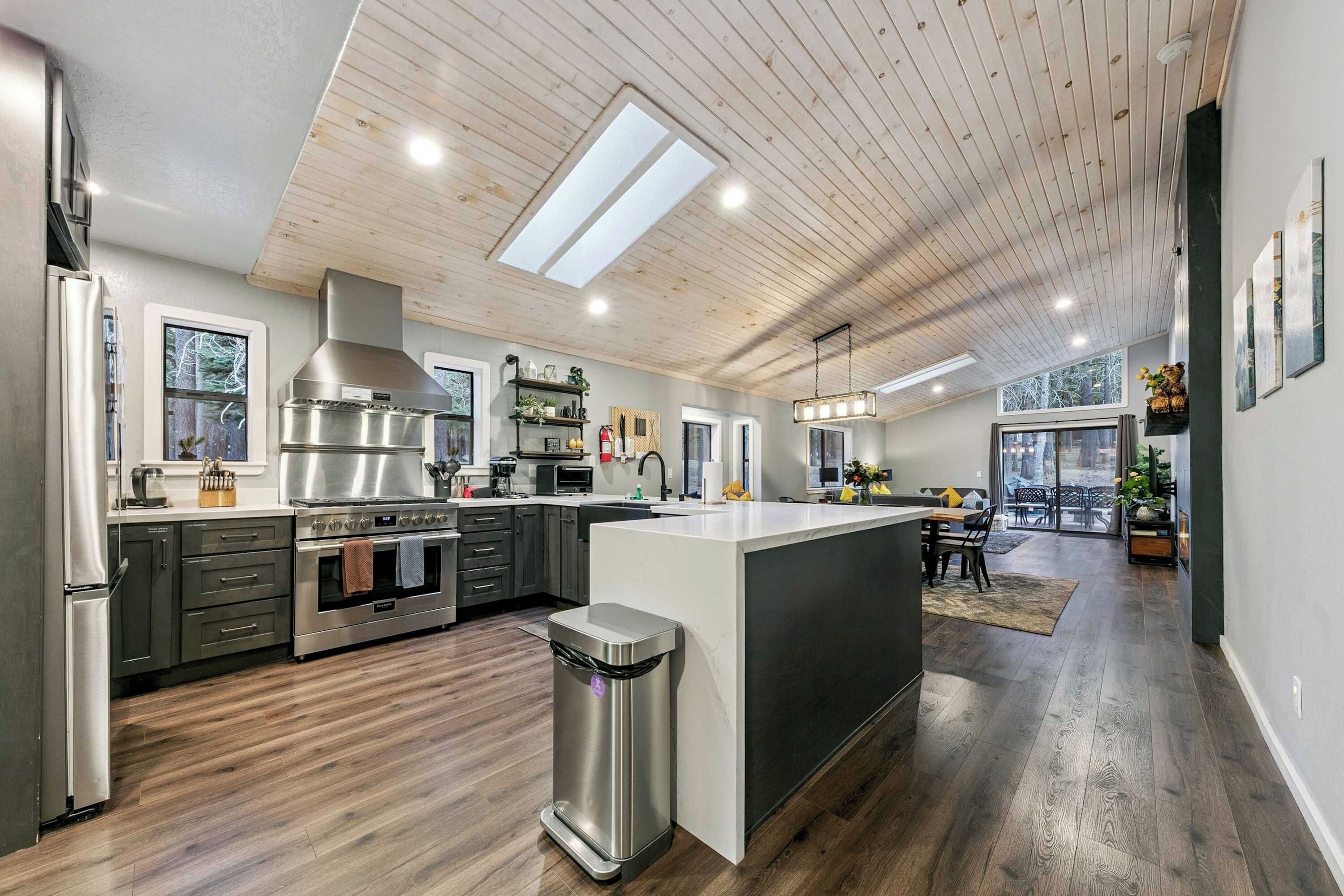 A modern kitchen with a central island, stainless steel appliances, and a view to the outdoors.