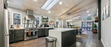 A modern kitchen with a central island, stainless steel appliances, and a view to the outdoors.