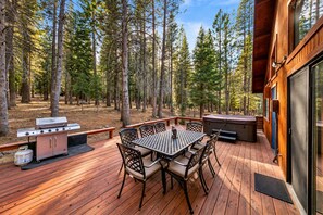 An outdoor deck with a grill, seating, and a hot tub.