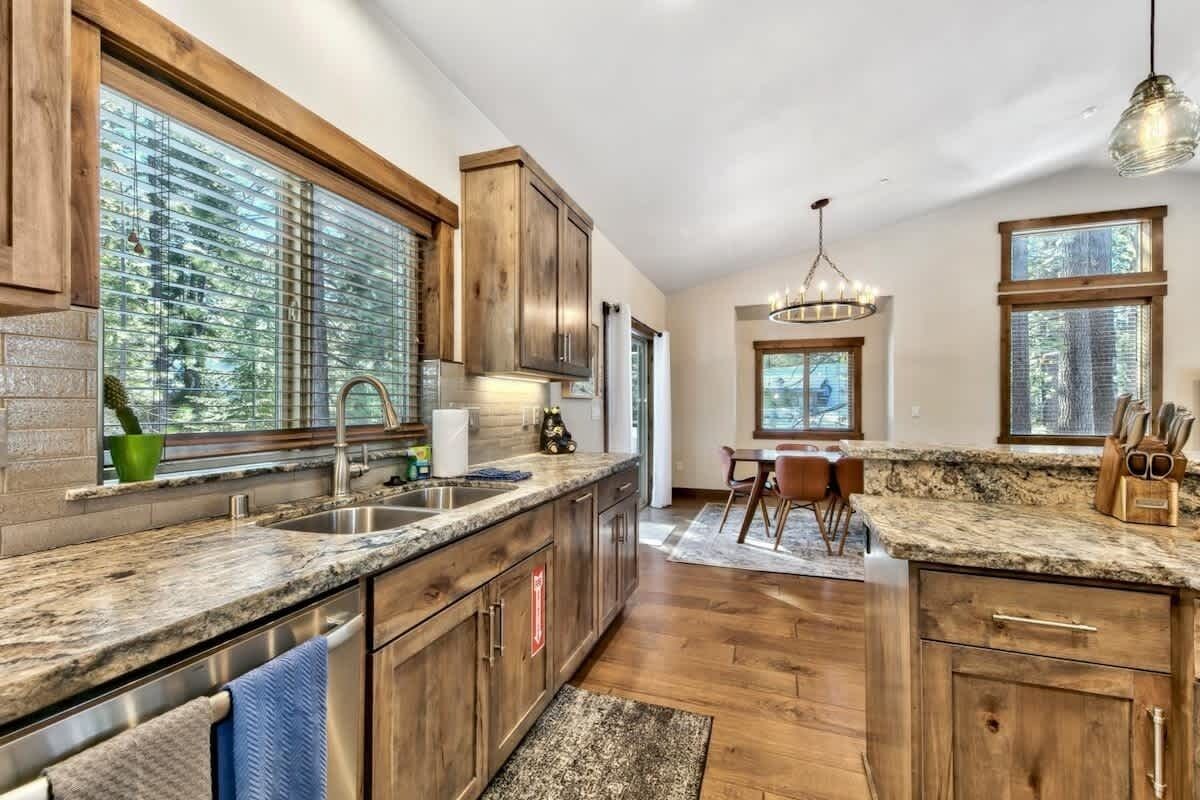 A modern kitchen with wooden cabinets, granite countertops, and large windows.