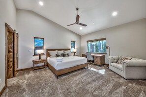 Quarto com uma cama grande, uma escrivaninha, uma cadeira e um ventilador de teto.
