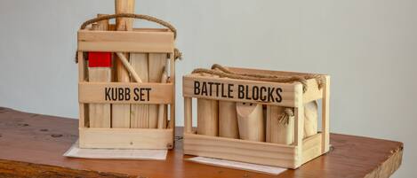 Two wooden crates labeled 'KUBB SET' and 'BATTLE BLOCKS' on a wooden surface.