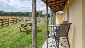 An outdoor patio area with a wooden fence, picnic table, and metal chairs. - Hidden Valley Getaway (Martinborough)