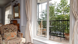 Una stanza con una grande finestra, un balcone con mobili da esterno e un divano in stile vintage con rivestimento floreale.
