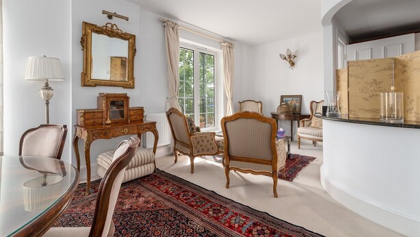 Un soggiorno spazioso con un'ampia finestra, arredamento elegante e uno specchio decorativo.