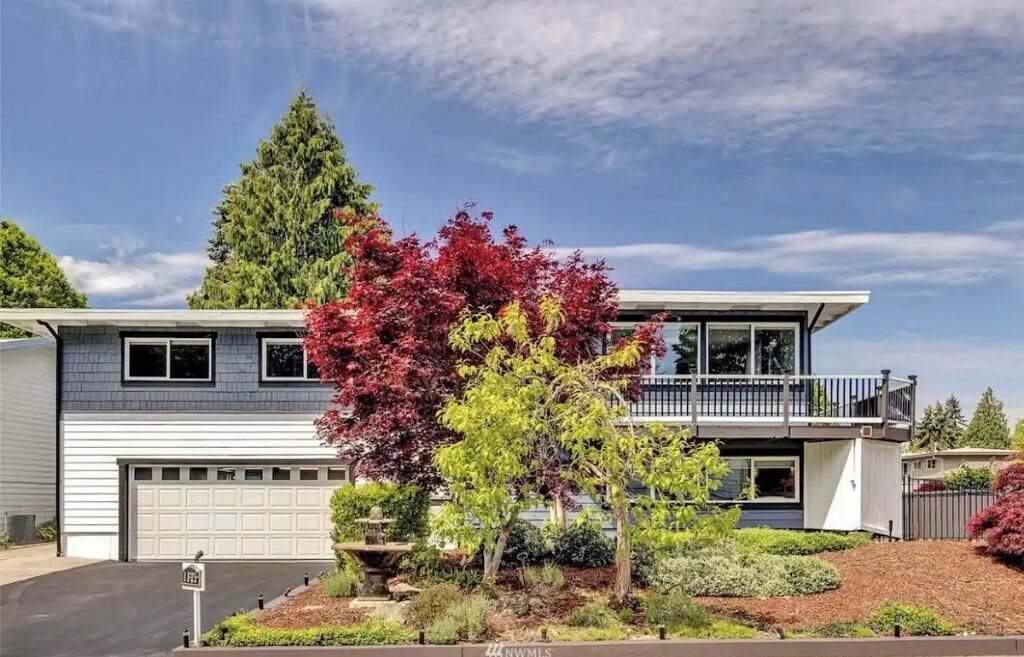 A modern two-story house with a garage, a balcony, and a well-maintained garden.